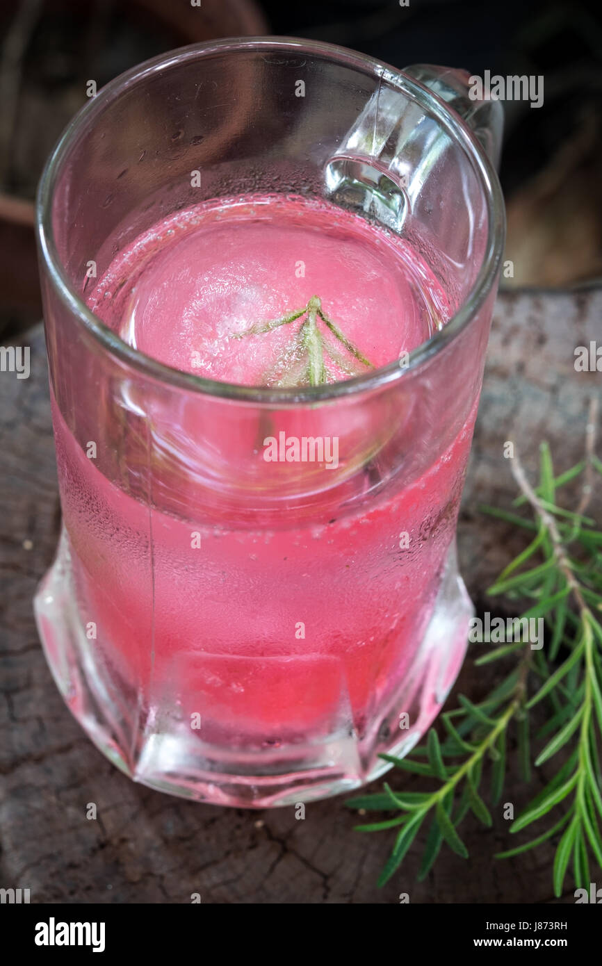 Aroma di lampone ghiaccio in acqua di soda decorate con rosmarino posto sul moncone di legno Foto Stock