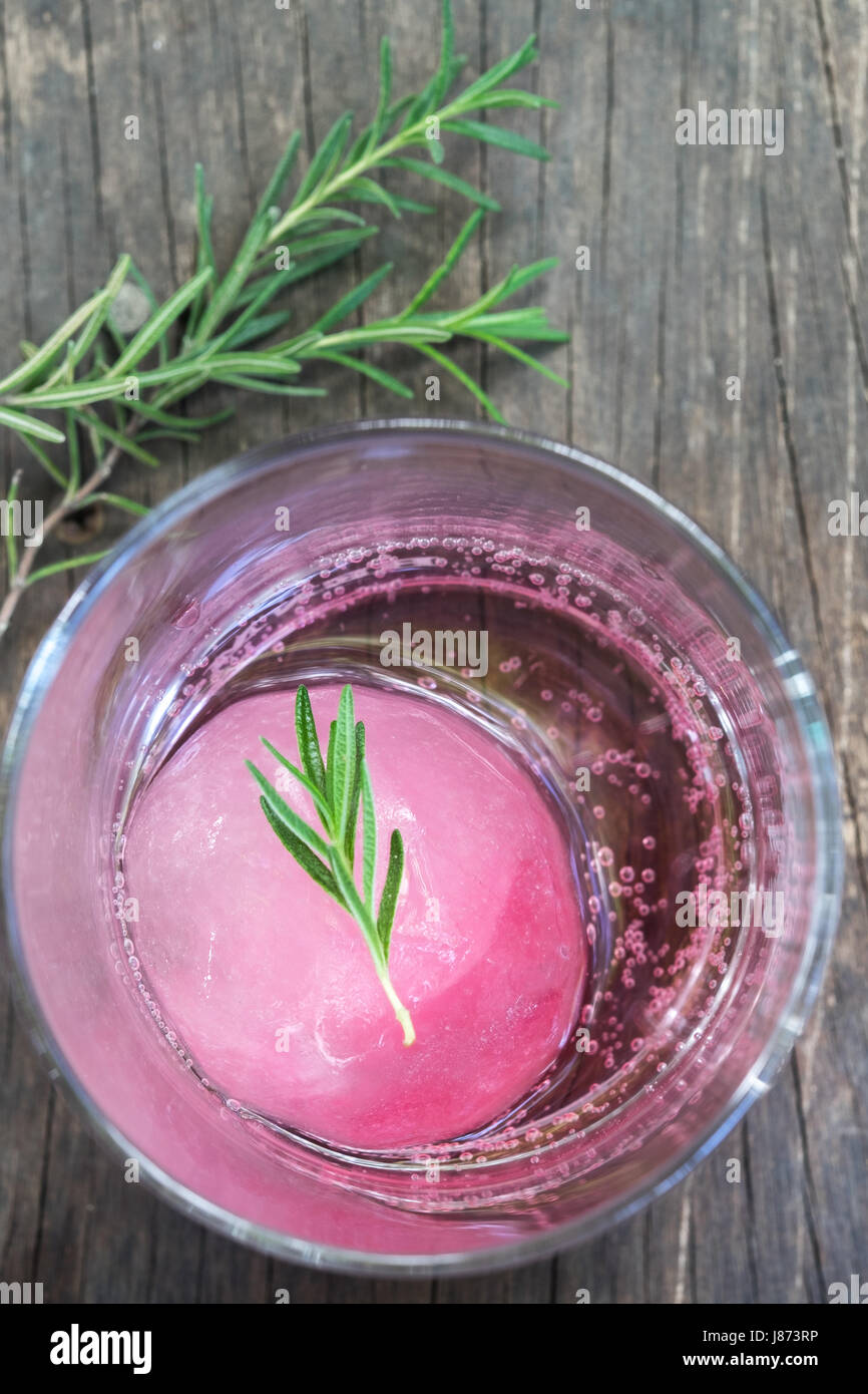 Aroma di lampone ghiaccio in acqua di soda decorate con rosmarino posto sul moncone di legno Foto Stock