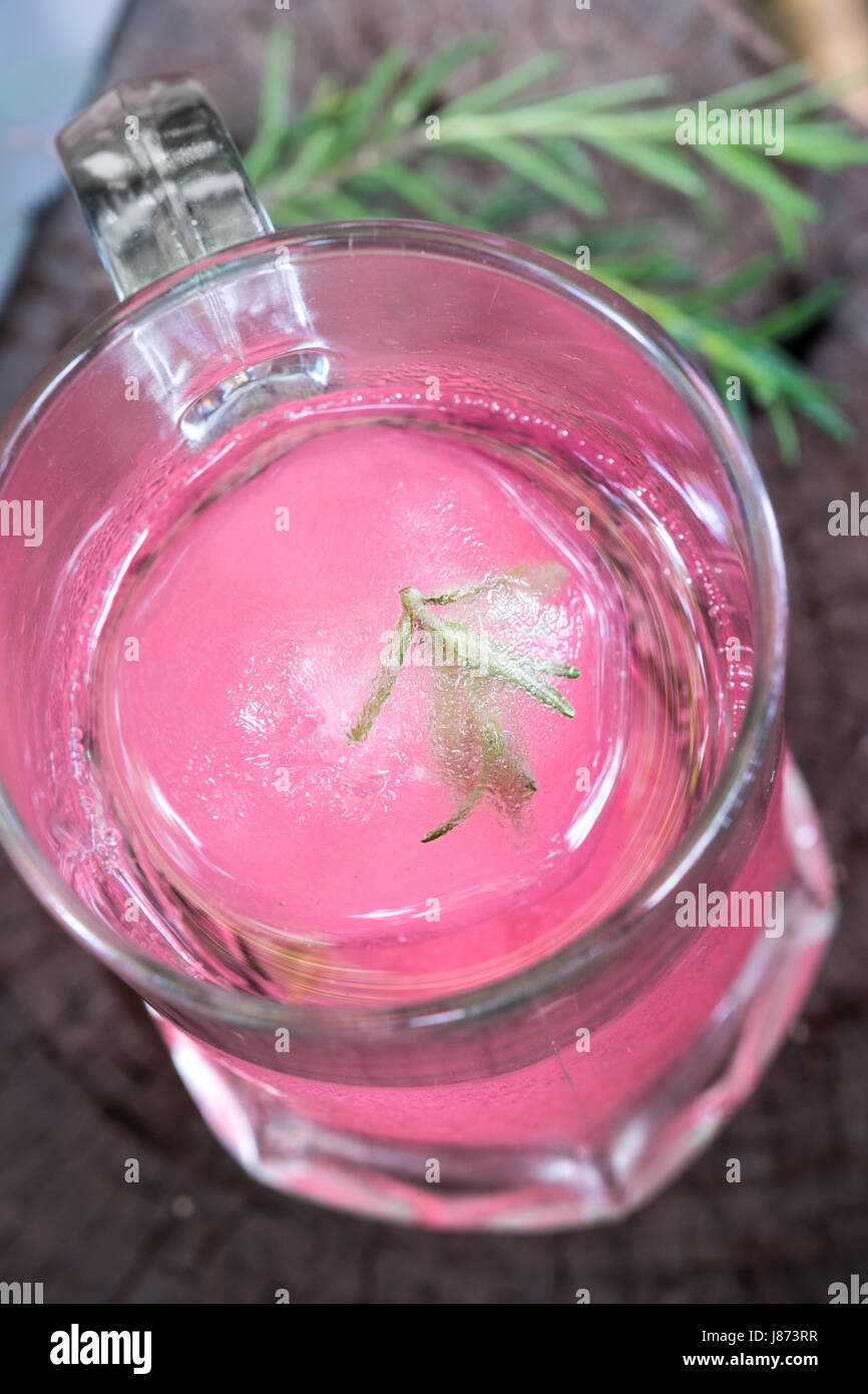 Aroma di lampone ghiaccio in acqua di soda decorate con rosmarino posto sul moncone di legno Foto Stock