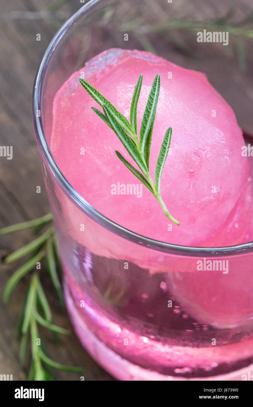 Aroma di lampone ghiaccio in acqua di soda decorate con rosmarino posto sul moncone di legno Foto Stock