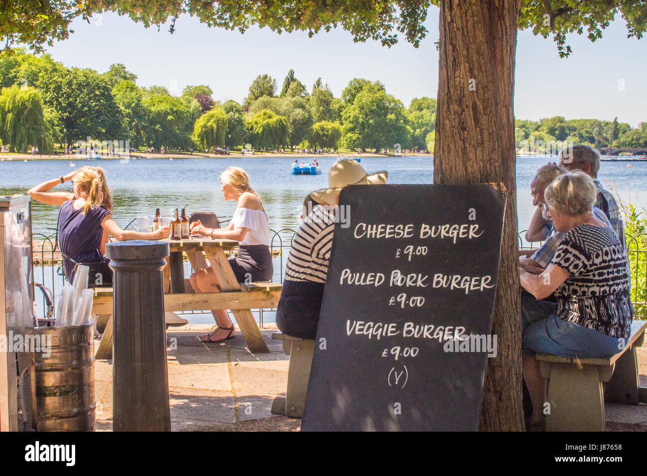 La gente seduta in un ristorante esterno dal lago a serpentina in Hyde Park, Londra Foto Stock
