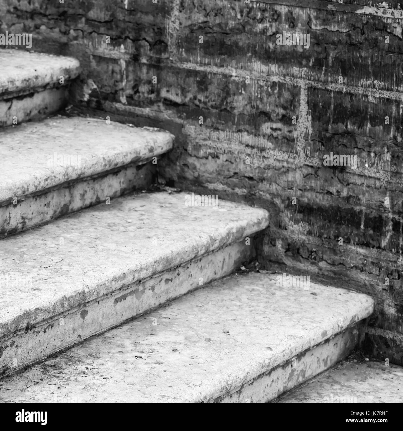 Vecchia scalinata in cemento va vicino a un muro di mattoni, foto in bianco e nero Foto Stock