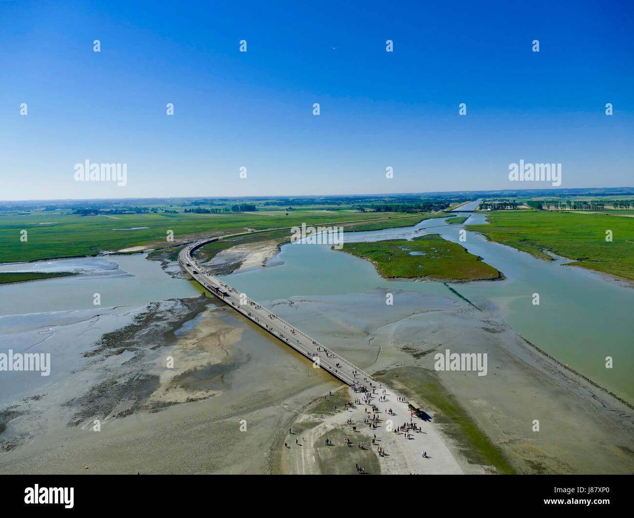 Guardando verso il basso dal Mont Saint-Michel come persone sciame di avanti e indietro attraverso il ponte sopra il fiume Couesnon. Mont Saint Michel, Francia. Foto Stock