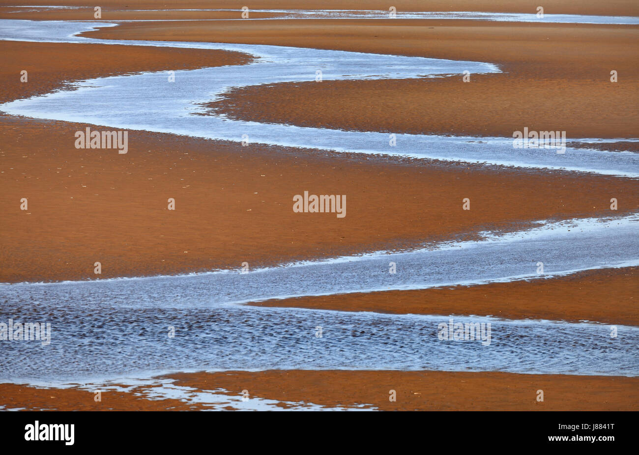 Serpeggianti canale ow acqua a bassa marea sulla spiaggia Heacham con la bassa marea. Foto Stock