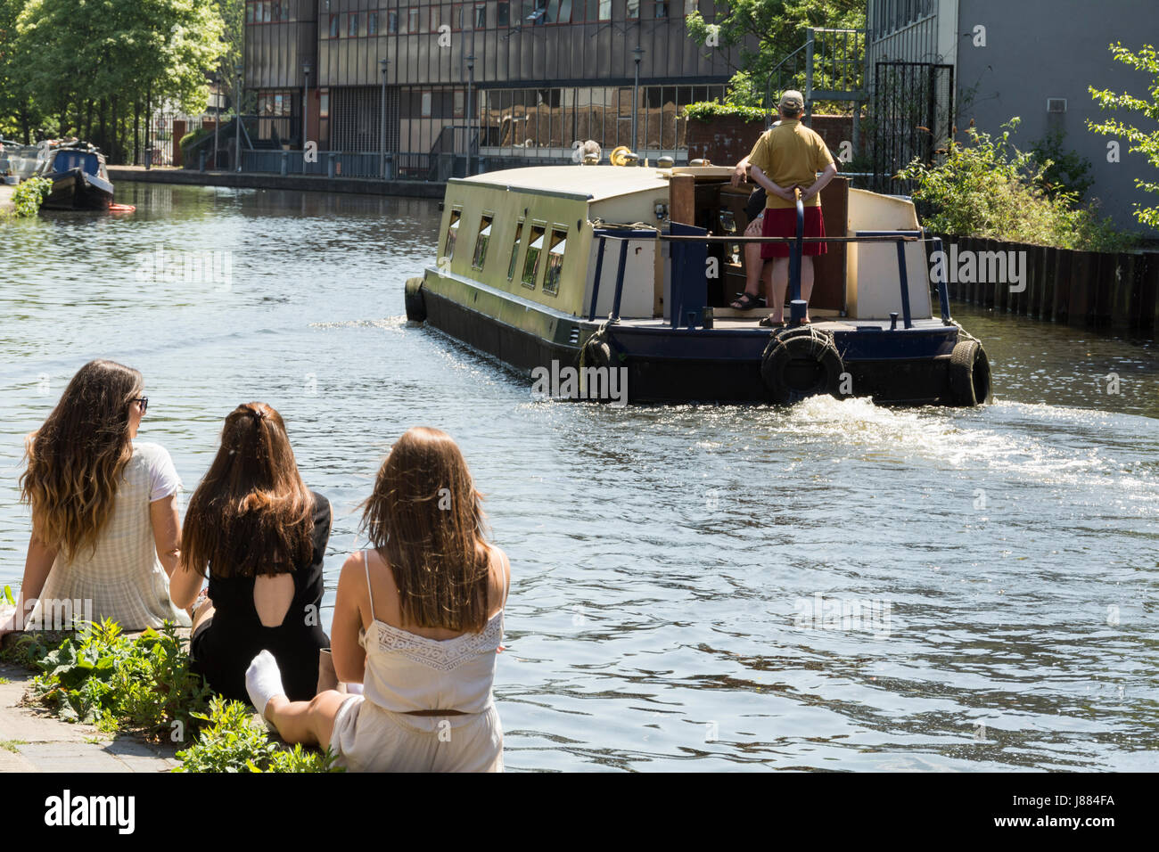 Tre giovani donne seduti su un canale banca in King's Cross, London, Regno Unito Foto Stock