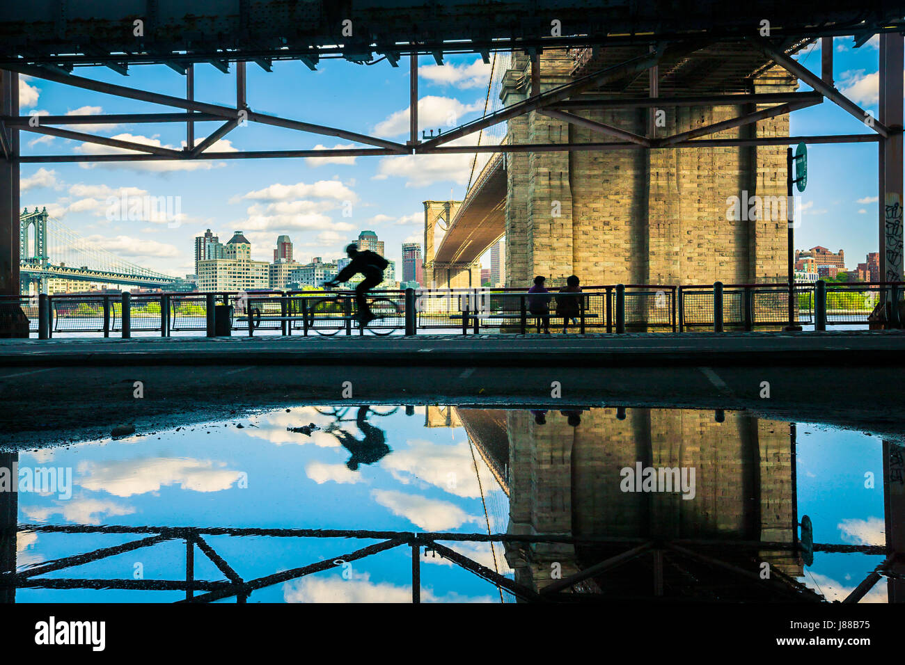 La riflessione di acqua del ciclista e il Ponte di Brooklyn a New York City Foto Stock