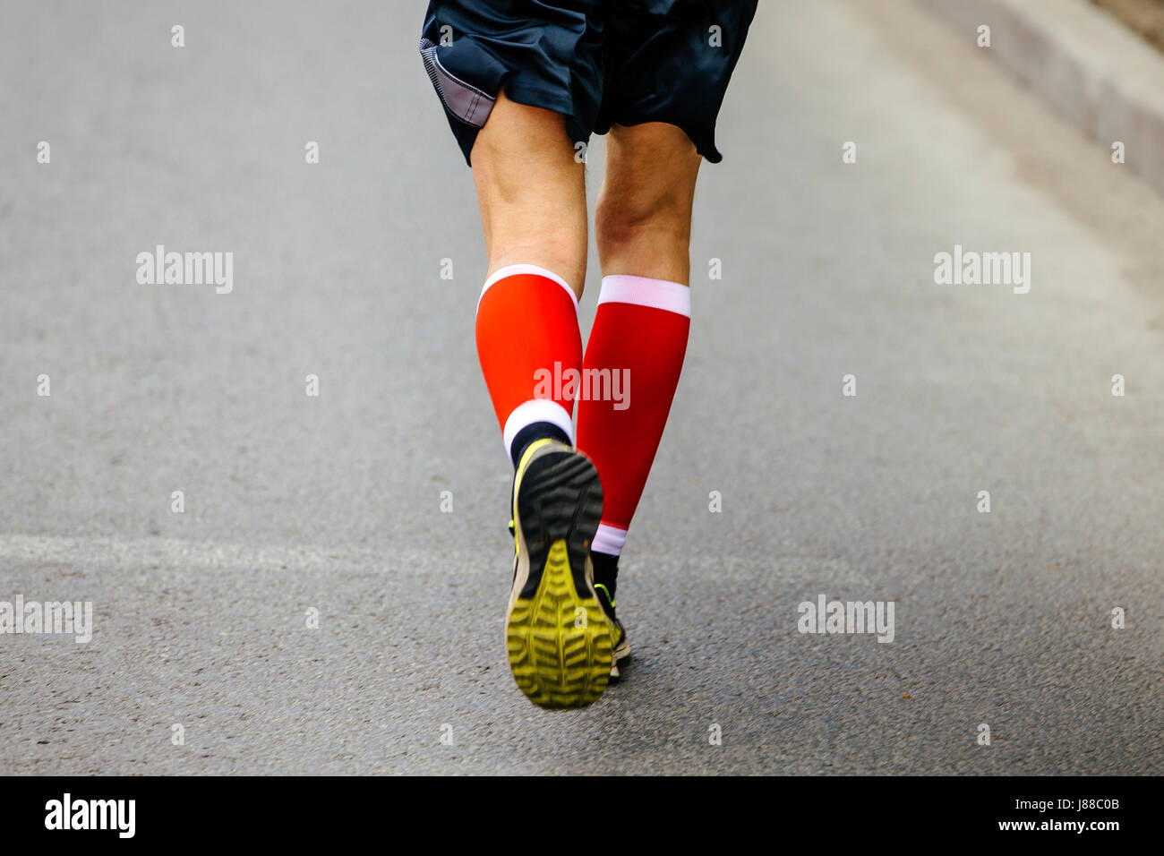 Piedi posteriori uomini runner in rosso calze di compressione in funzione street Foto Stock