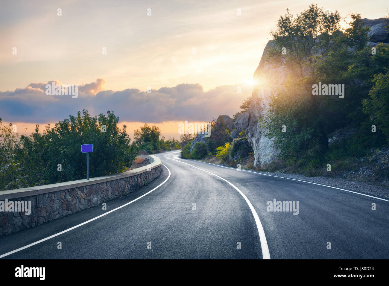 Strada di Montagna. Paesaggio con rocce, cielo sereno con le nuvole e la bella strada asfaltata in serata d'estate. Tonificazione vintage. Sfondo di viaggio. Hig Foto Stock