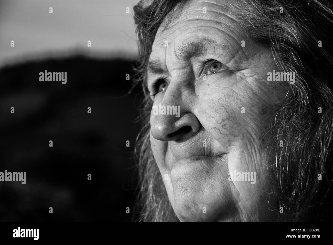 Chiudere un ritratto in bianco e nero di una vecchia donna che guarda il cielo. Foto Stock