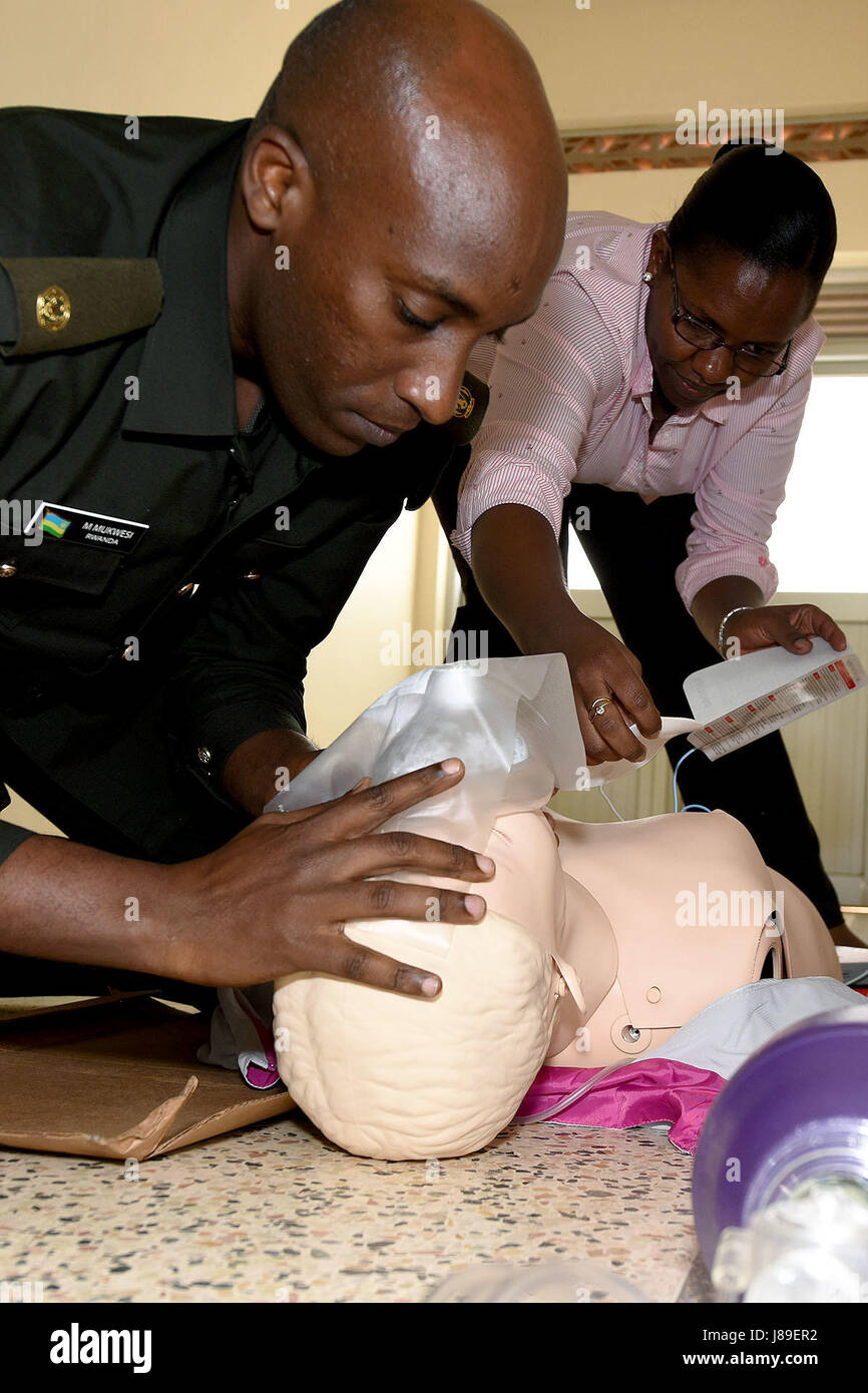 Il Mag. Christian Mukwesi, MD (anteriore), mostra il modo corretto per aprire le vie respiratorie mentre Gisele Mudasumbwa, RN (retro) applica il defibrillatore automatico esterno pad usando un manichino durante il Basic Life Support certificazione presso l'ospedale militare di Kigali, Ruanda il 2 maggio. Basic Life Support e Advanced Cardiac Life Support sono parte della fase quattro della difesa Istituto per le operazioni mediche programma finanziato dall'Africano di istruzione militare per stabilire in maniera affidabile un centro di simulazione per il Ruanda ospedale militare a sostegno delle Nazioni Unite per operazioni di mantenimento della pace. Foto Foto Stock