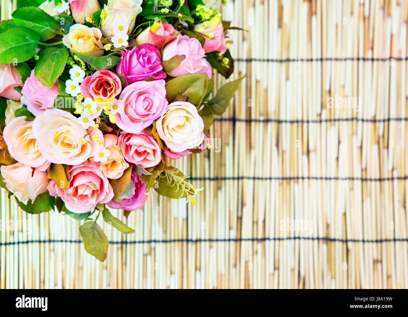 In prossimità dei bellissimi artificiali rose multicolore bouquet di fiori decorato sul tappetino di bambù texture utilizzare come spazio di copia,sfondo ,sfondo Foto Stock