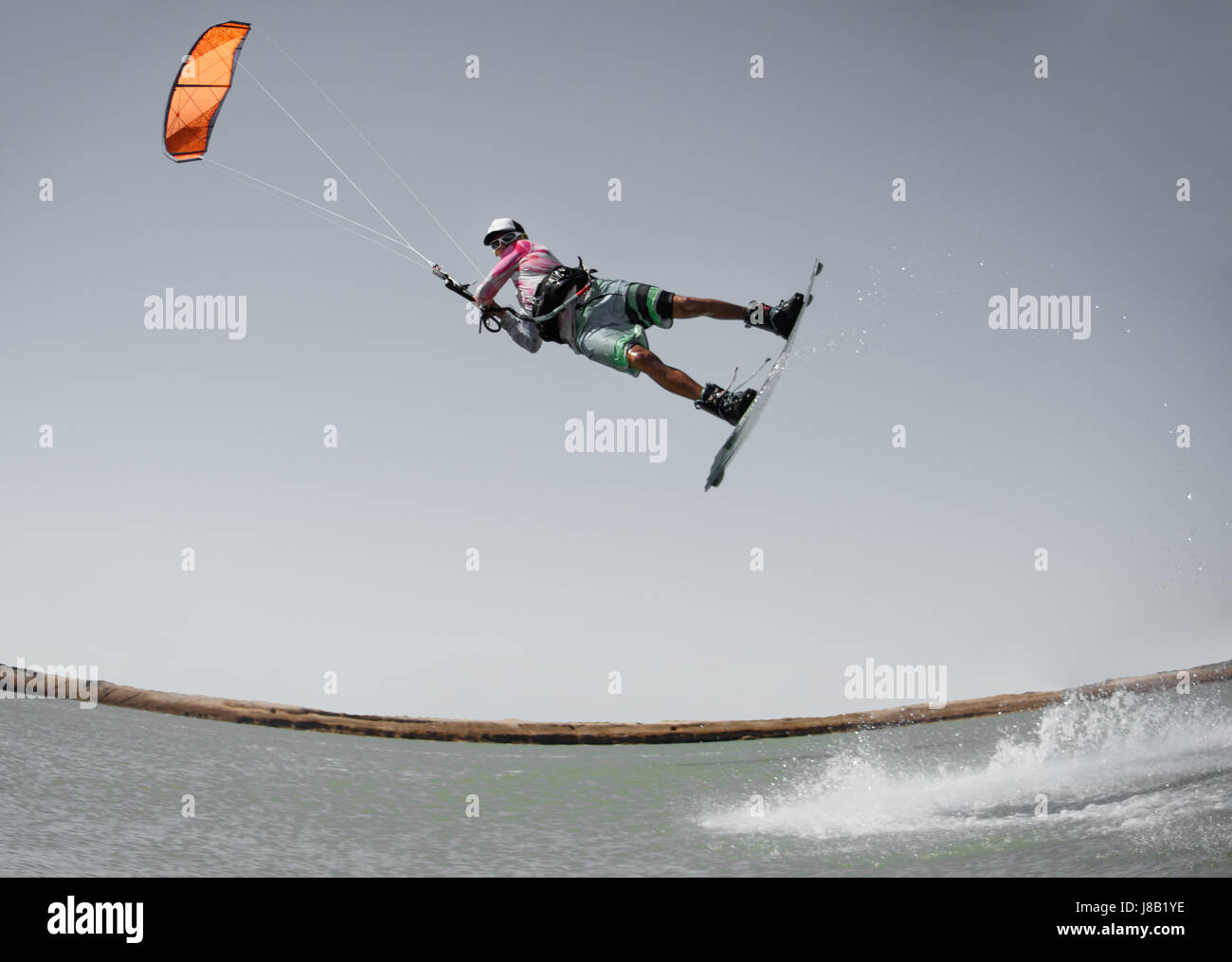 Professional kitesurf rider sportivo salta di alta acrobazia kiteboarding raley trucco con un enorme spruzzo d'acqua. Attività ricreative e di estrema Foto Stock