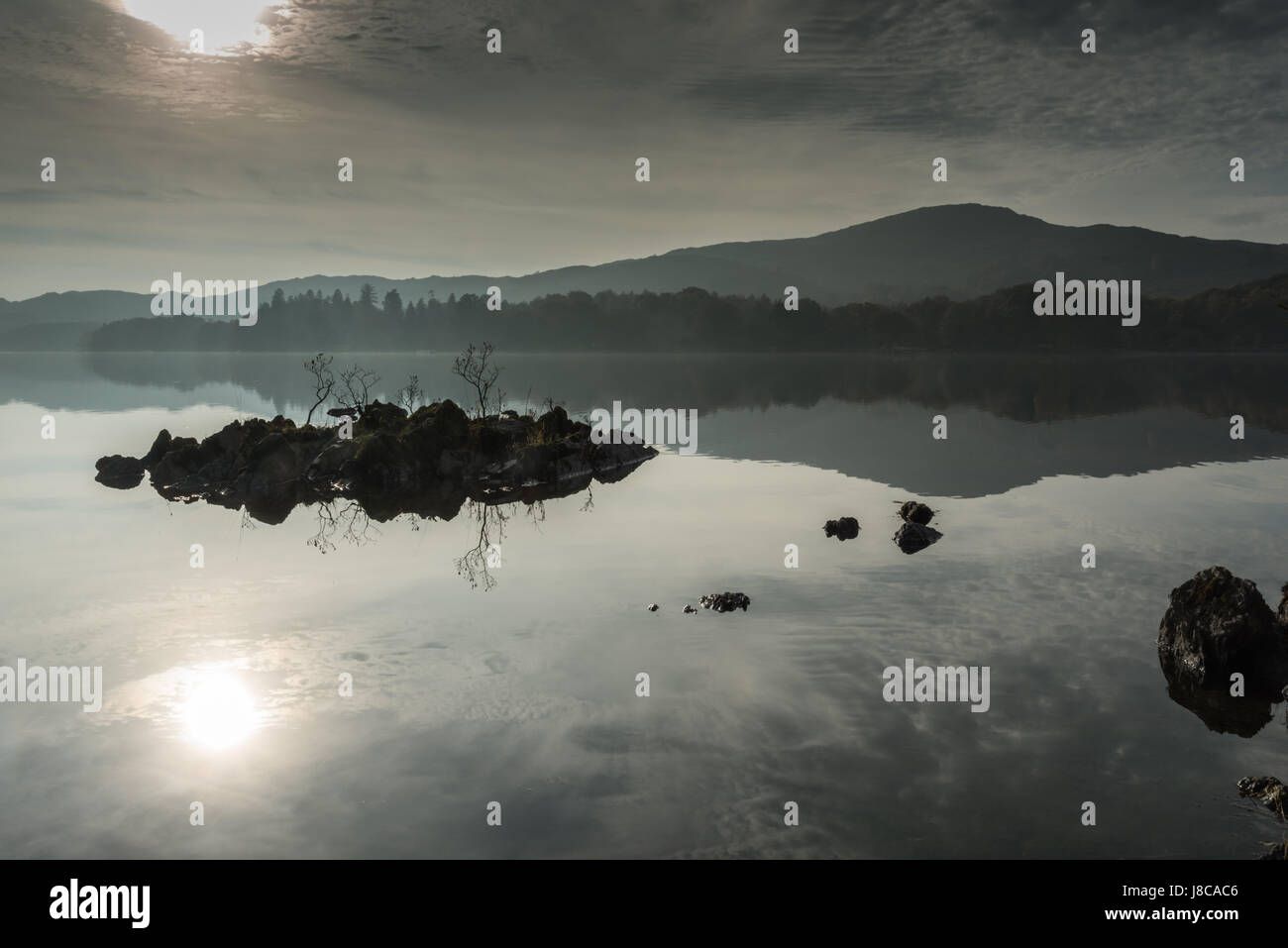 Nebbiosa mattina autunnale con riflessioni in Coniston Water nel Lake District inglese, Regno Unito Foto Stock