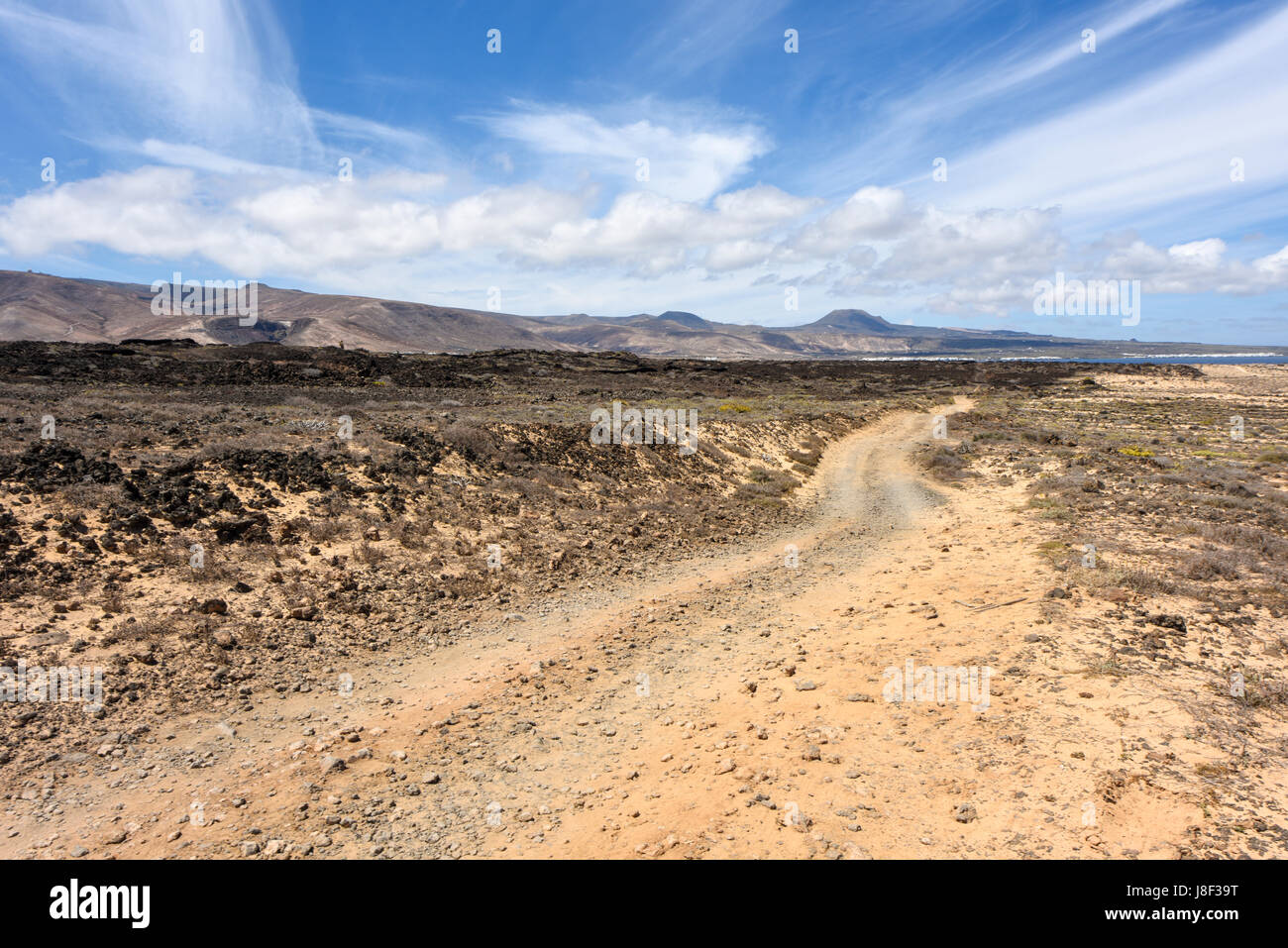 Strada di ghiaia attraverso la mozzafiato a nord-ovest della zona costiera di Lanzarote. Spagna Foto Stock