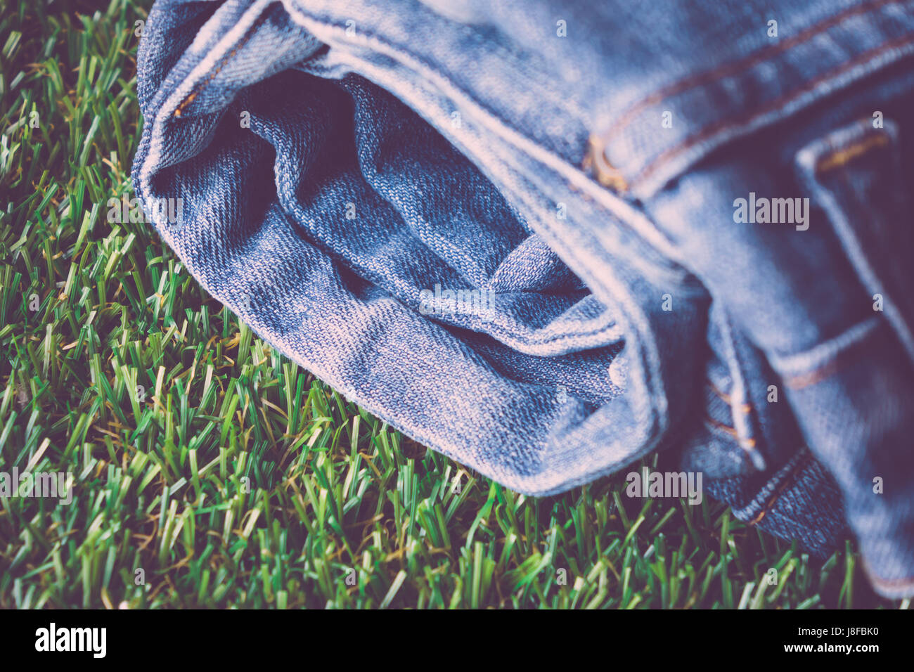 Jeans blu ripiegato sull'erba. Foto Stock