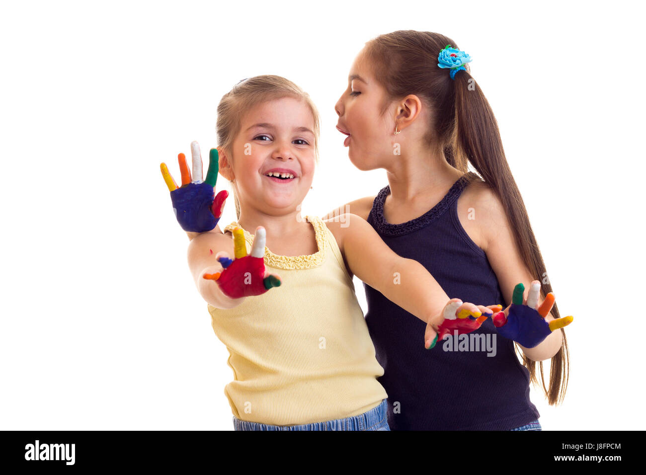 Due poco positive le ragazze in giallo e nero camicie con ponytails e mani colorate su sfondo bianco in studio Foto Stock