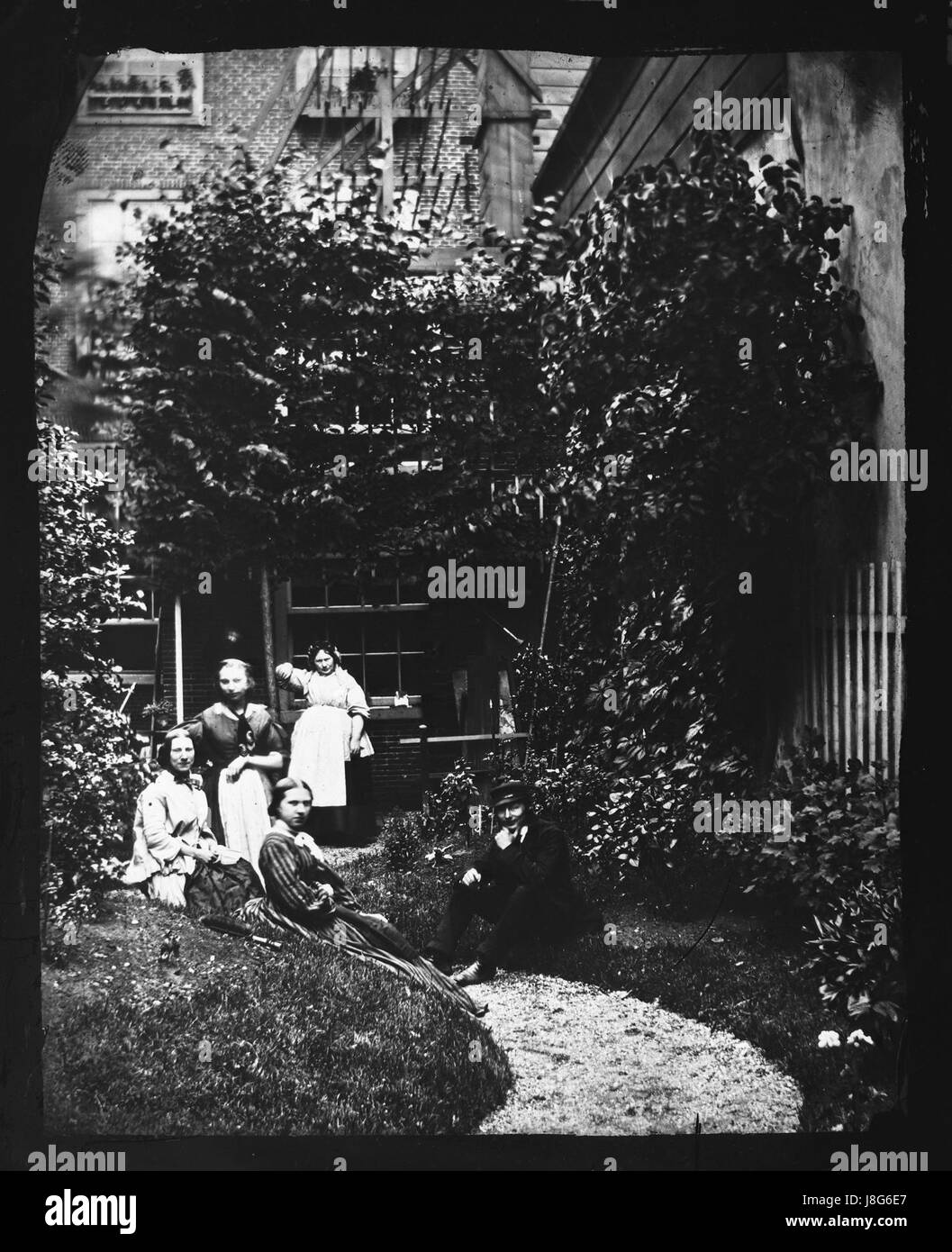 Questo titolo olandese si traduce in "Ritratto di gruppo in un giardino in abbigliamento quotidiano, 1860-1870". Raffigura un raduno di individui in un giardino, indossando abiti ordinari tipici del periodo, offrendo uno sguardo alla vita sociale durante la fine del XIX secolo. Foto Stock