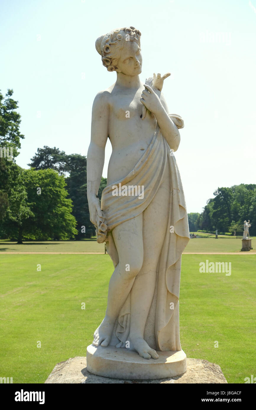 Questa immagine cattura una scultura di una fanciulla che tiene un uccello e fiori al Wrest Park nel Bedfordshire, in Inghilterra. Il parco è noto per il suo paesaggio storico e le eleganti statue, che rappresentano le tradizioni artistiche del XVIII secolo. Foto Stock