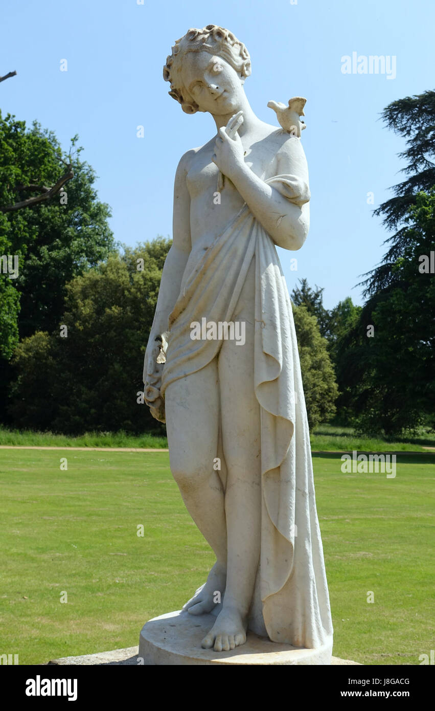 Questa fotografia mostra una statua di una fanciulla con un uccello e fiori, situata a Wrest Park nel Bedfordshire, Inghilterra. La statua è un notevole esempio di scultura classica, spesso ammirata per i suoi intricati dettagli e la serena rappresentazione della natura. Foto Stock