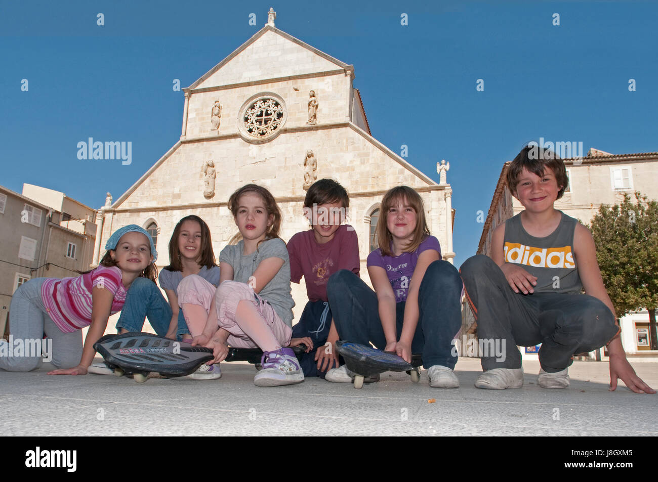 I bambini di fronte ad una chiesa medievale in Rab Croazia Foto Stock