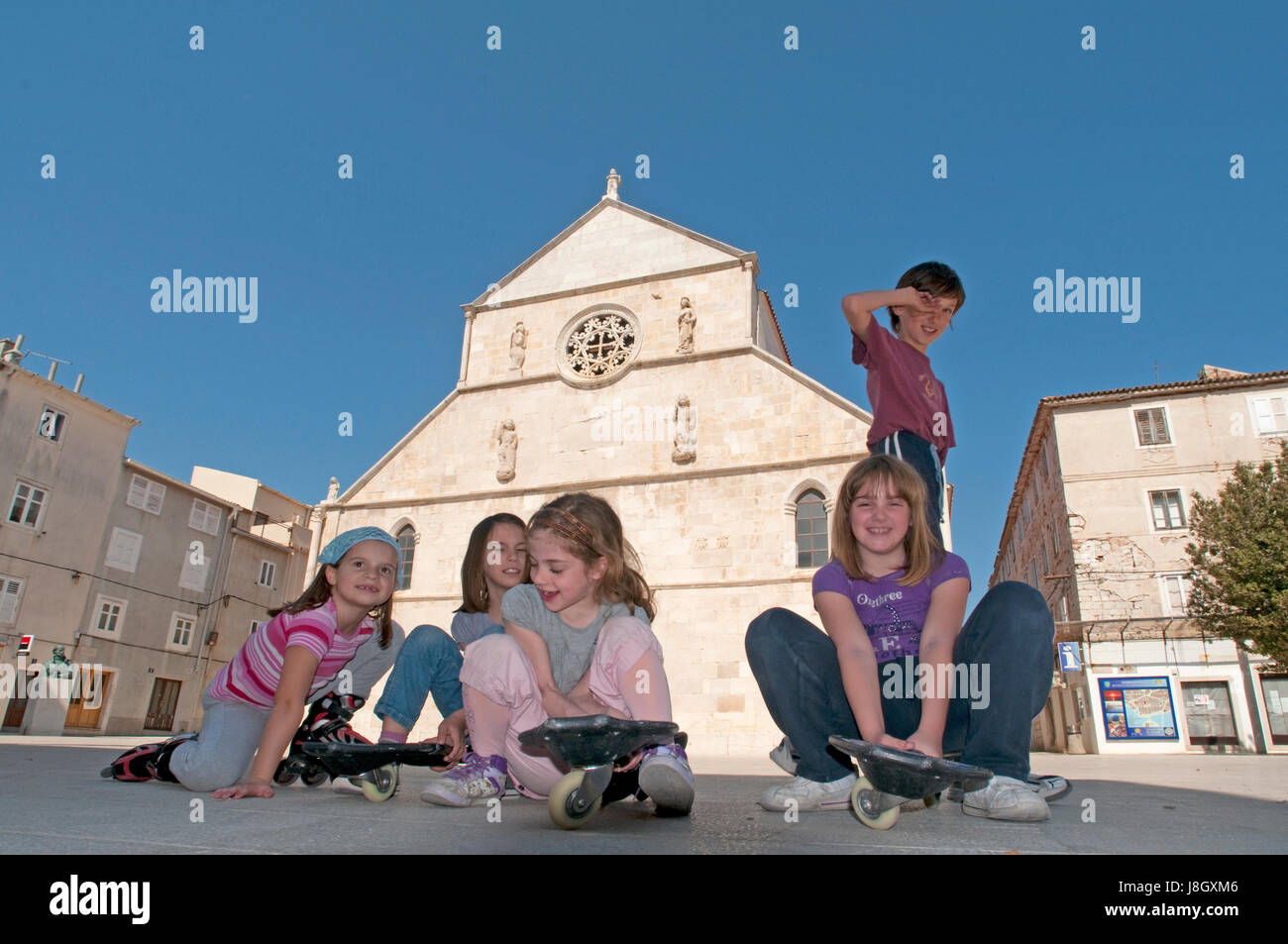 I bambini di fronte ad una chiesa medievale in Rab Croazia Foto Stock