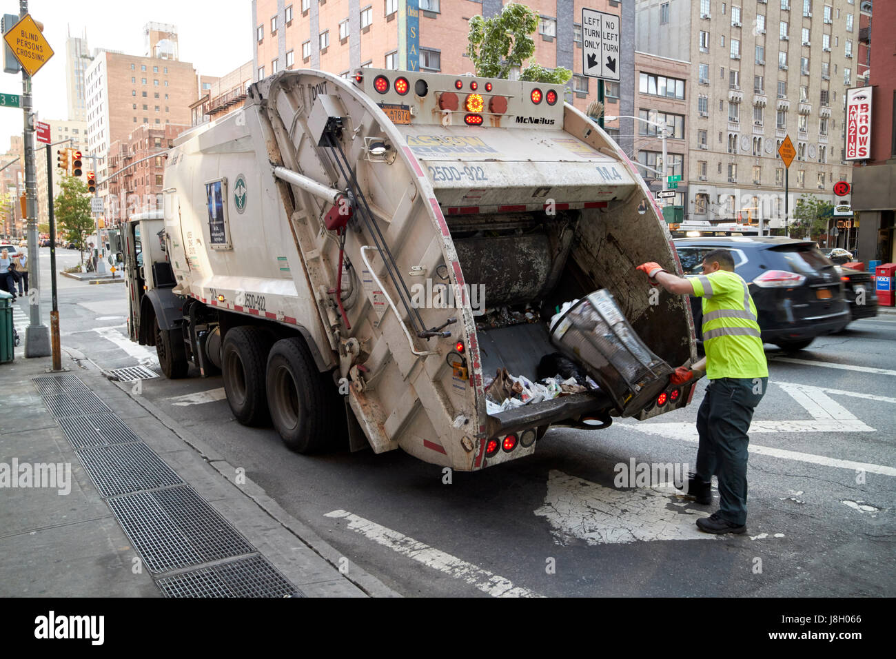 New York City discostarsi di igiene di lavoro strada di svuotamento cestino dei rifiuti nel rifiutare il camion della spazzatura USA Foto Stock