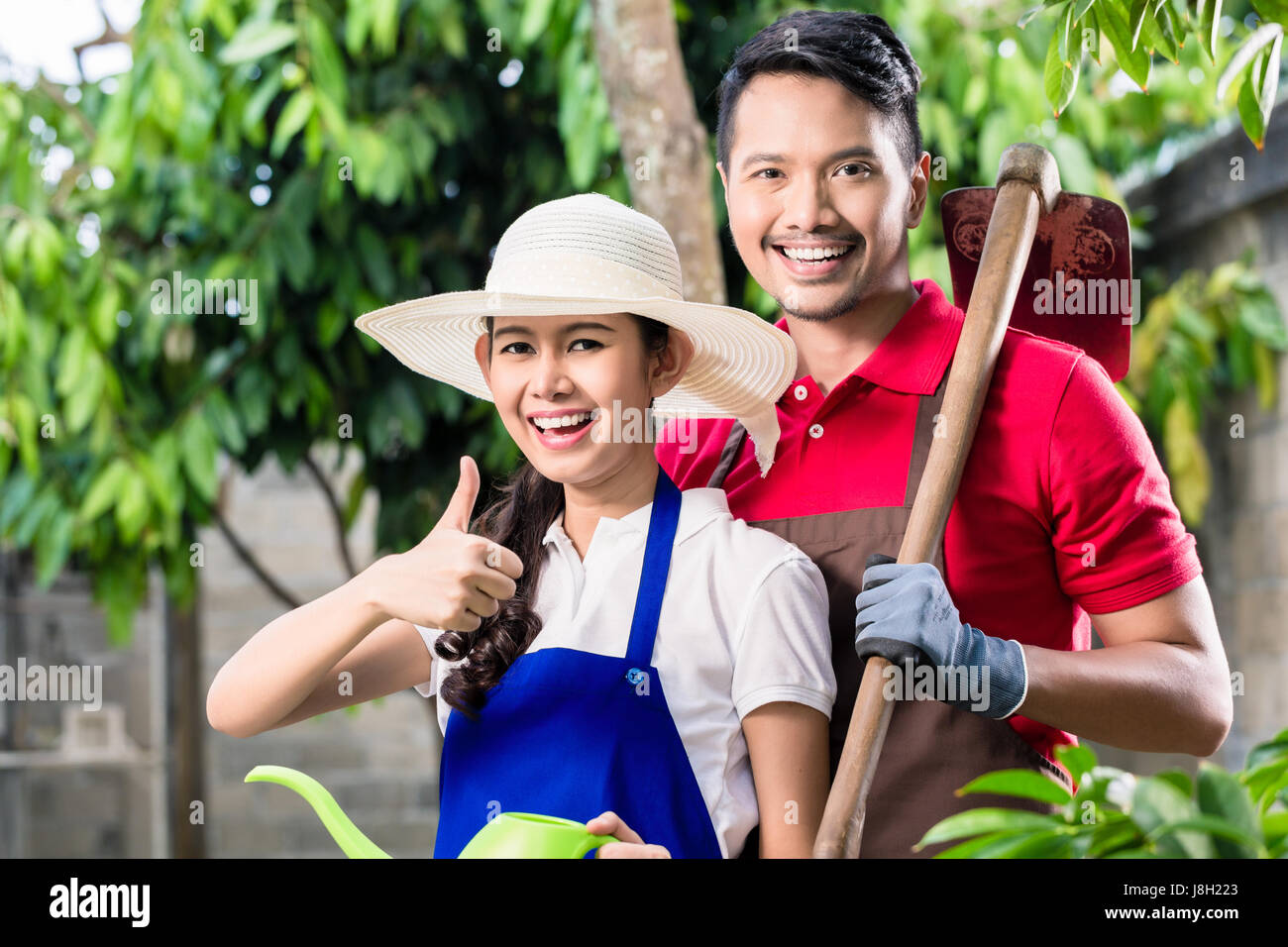 Giovani asiatici Coppia sorridente mentre si lavora in giardino Foto Stock