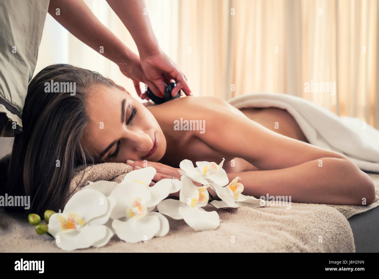 Giovane donna di ricevere un massaggio con pietre calde a spa e wellness cent Foto Stock