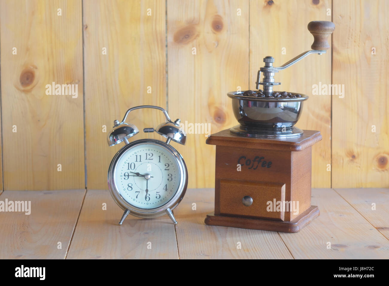Sveglia, il macinino da caffè, antichi su uno sfondo di legno. Foto Stock