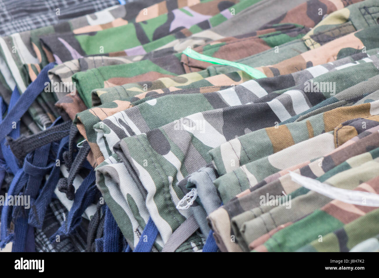 Pantalone mimetico varietà di vestiti appesi a cremagliera nella boutique. Foto Stock
