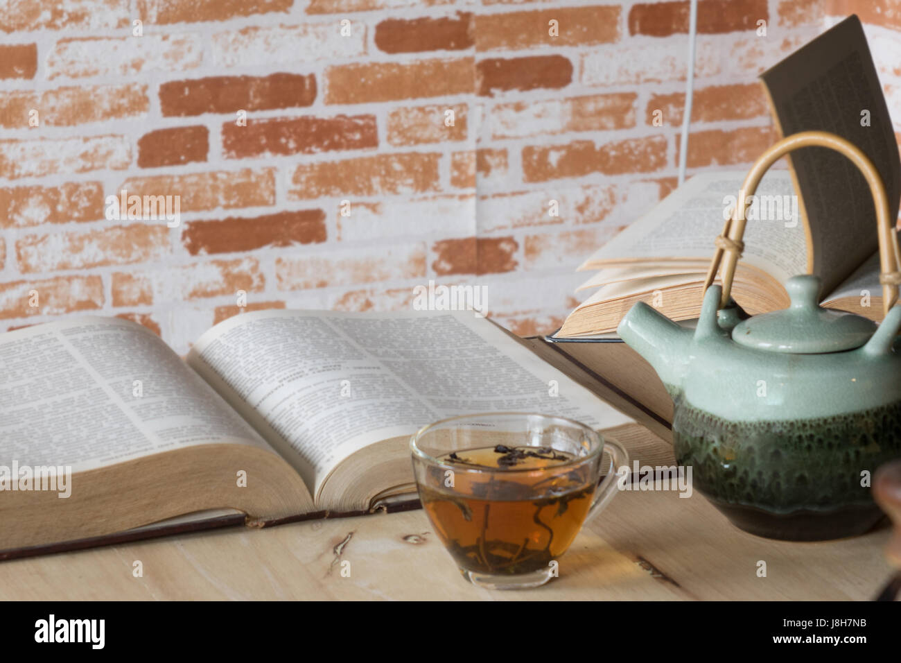 Il tè caldo con libri su uno sfondo di legno. Foto Stock