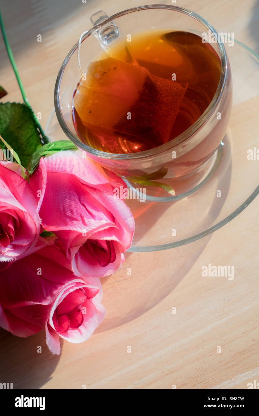 Rose fiori con tè caldo su di un tavolo di legno. Foto Stock