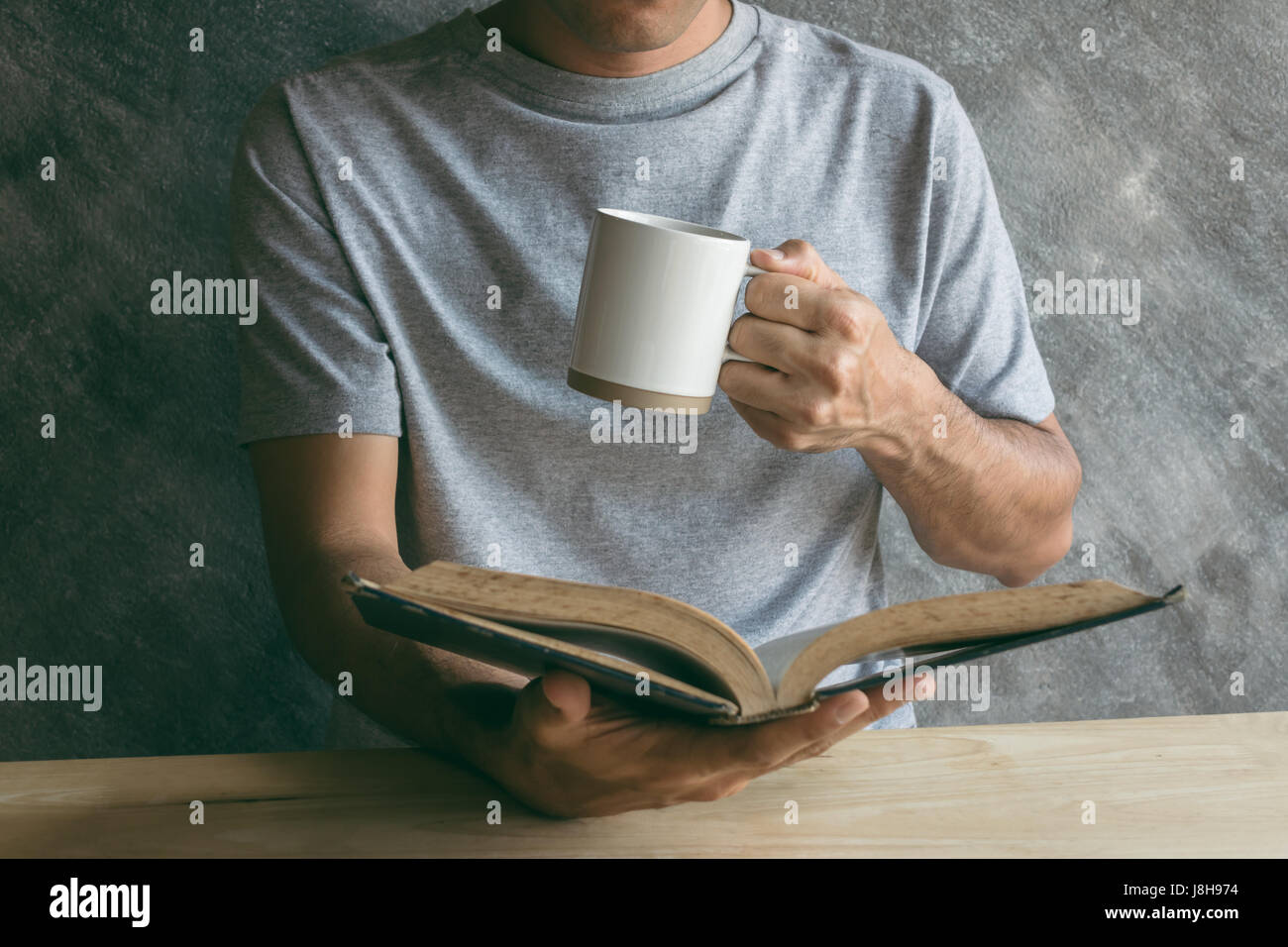 Tazza di caffè la carta la lettura di un libro su un tavolo di legno Foto Stock
