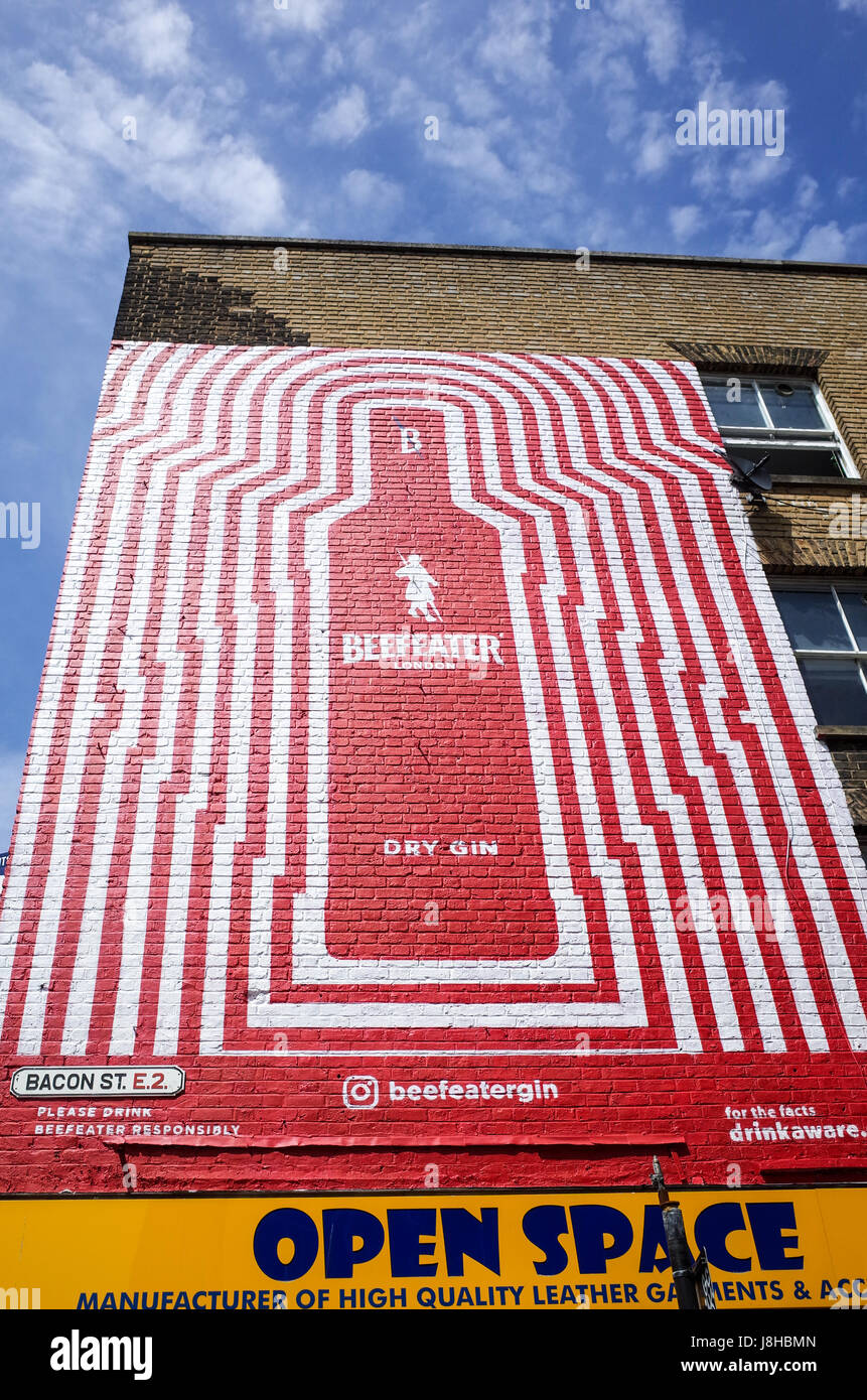 Un dipinta di fresco in stile graffiti annuncio per Beefeater Gin sul lato di un negozio di Brick Lane a Londra il popolare quartiere di Shoreditch, nell'East End. Foto Stock