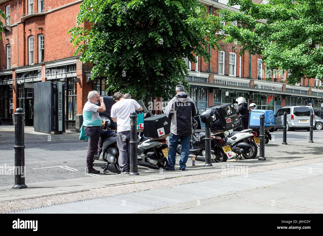 Deliveroo, Uber mangia e Stuart Consegna del cibo corrieri chat durante l'attesa per la consegna al cliente per le richieste. Foto Stock