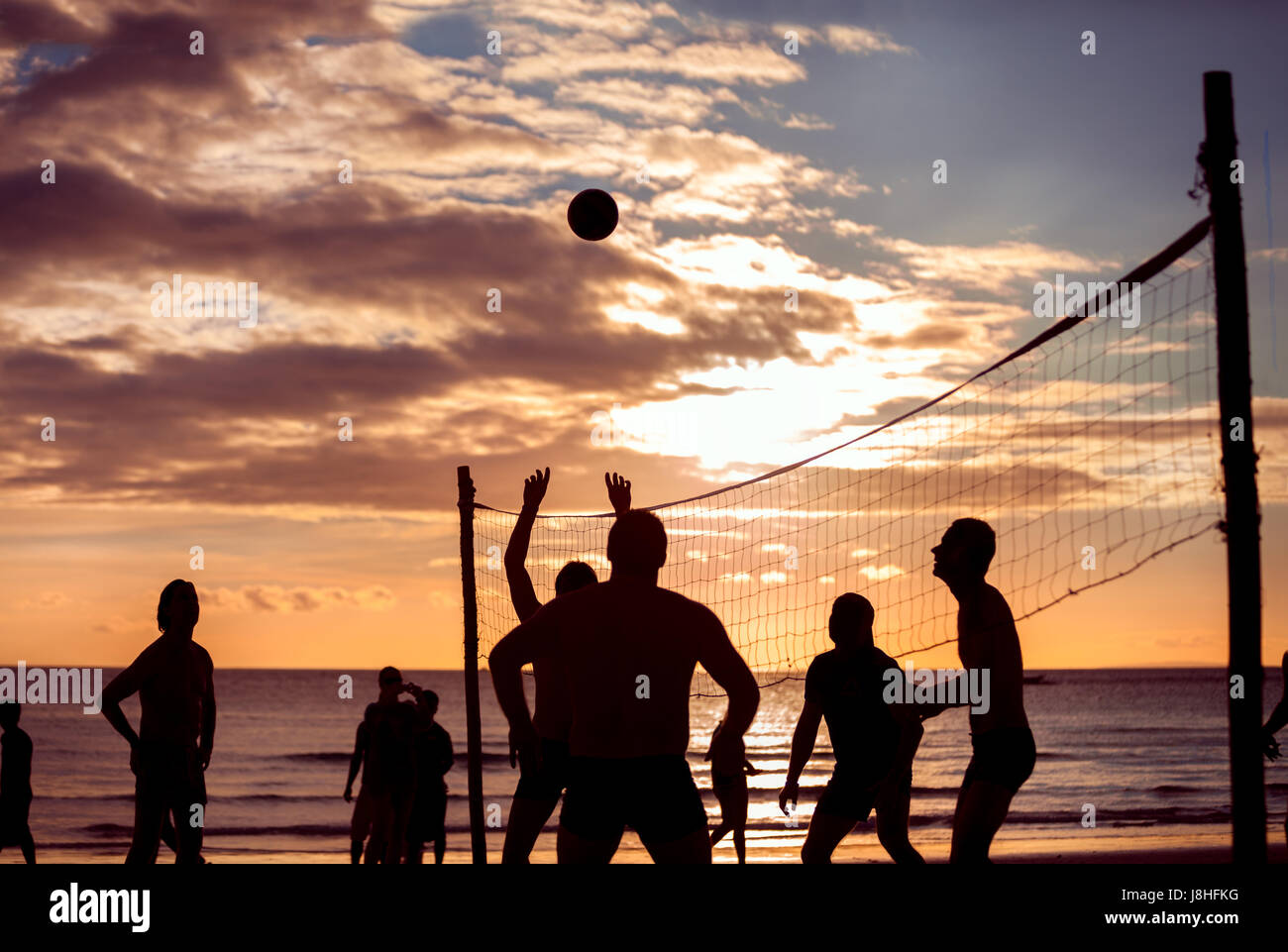 Silhouette a giocare a beach volley, tramonto Foto Stock