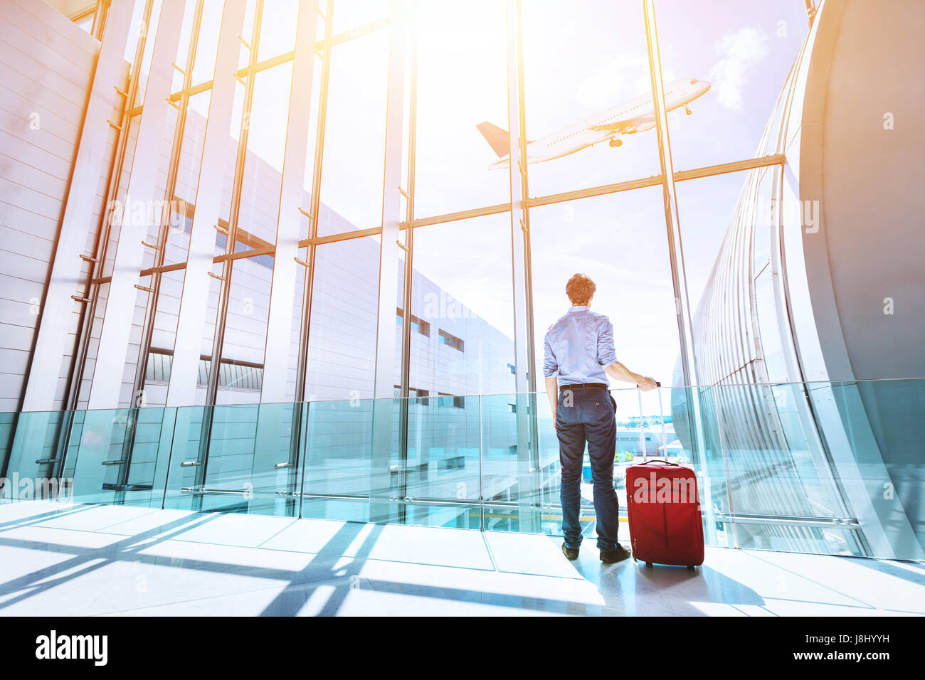 Imprenditore all'aeroporto terminale gate di imbarco guardando aereo attraverso la finestra Foto Stock