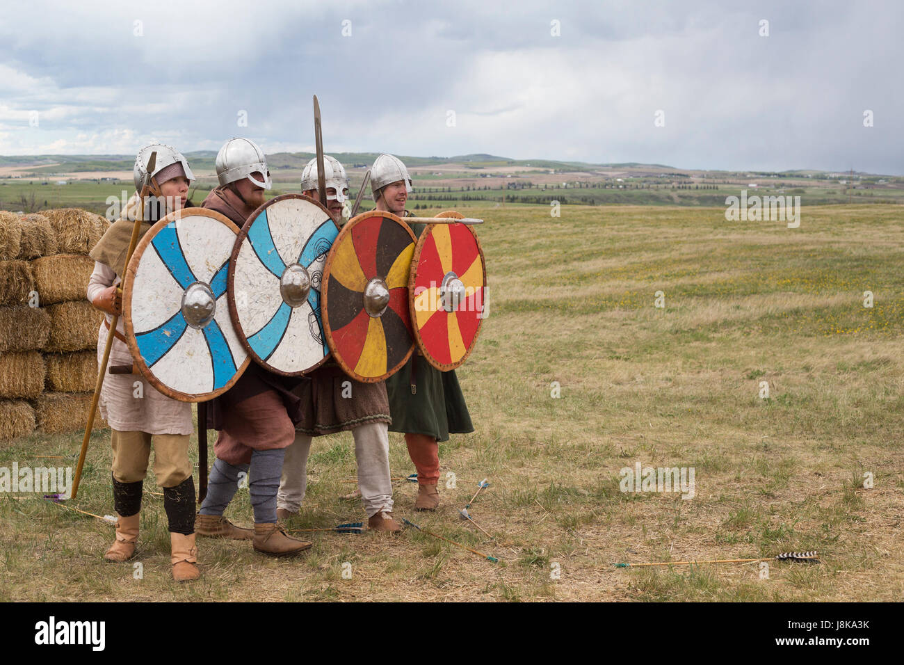 Donna e uomo rievoca la battaglia Viking, tenendo gli scudi e lance per difendersi dalle frecce volanti Foto Stock