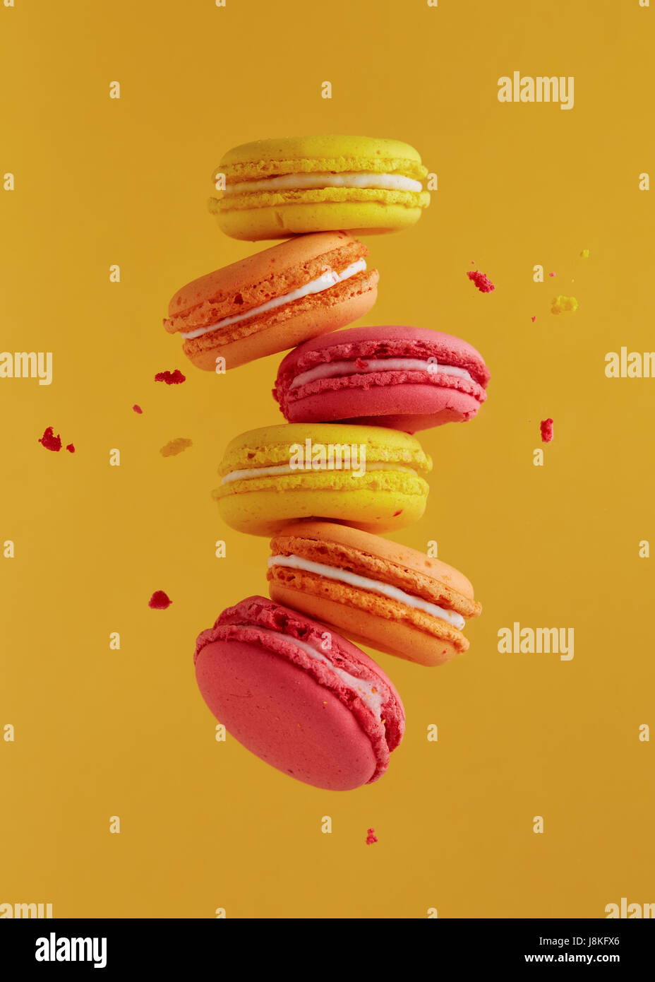 Diversi tipi di amaretti in movimento che rientrano su sfondo giallo. Dolce e colorata amaretti francese di caduta o battenti in movimento. Foto Stock