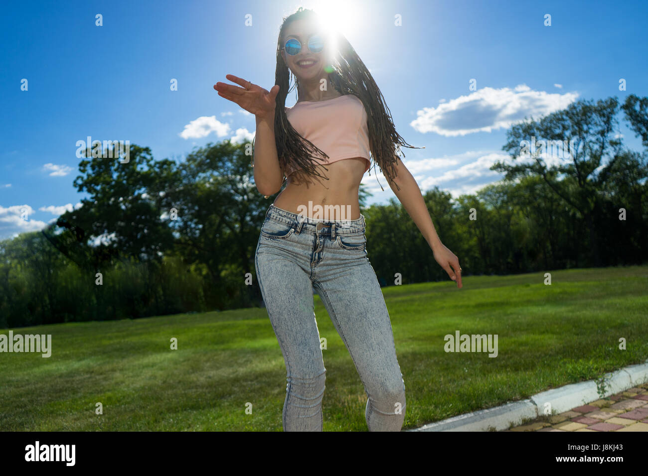 Carefree ragazza con zizi cornrows dreadlocks ballando sul prato verde Foto Stock