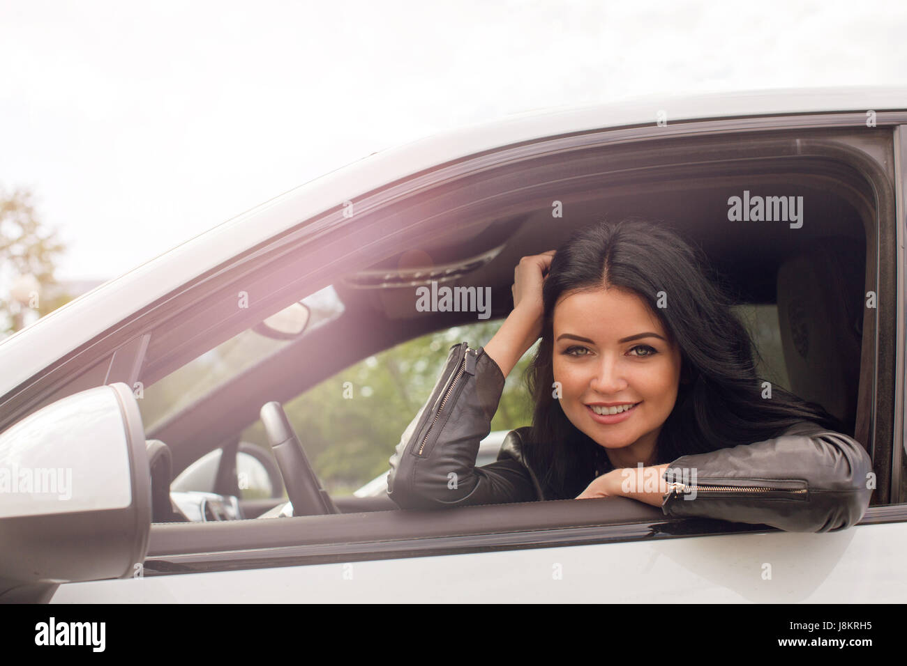 Piuttosto giovane donna seduta all'interno della vettura, sorridente verso la telecamera Foto Stock