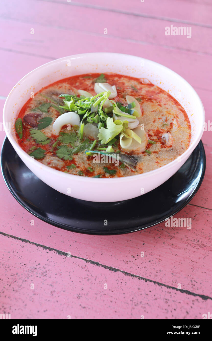 Tom Yum Goong in bianco ciotola di legno di rosa di alimenti sfondo tabella. Foto Stock