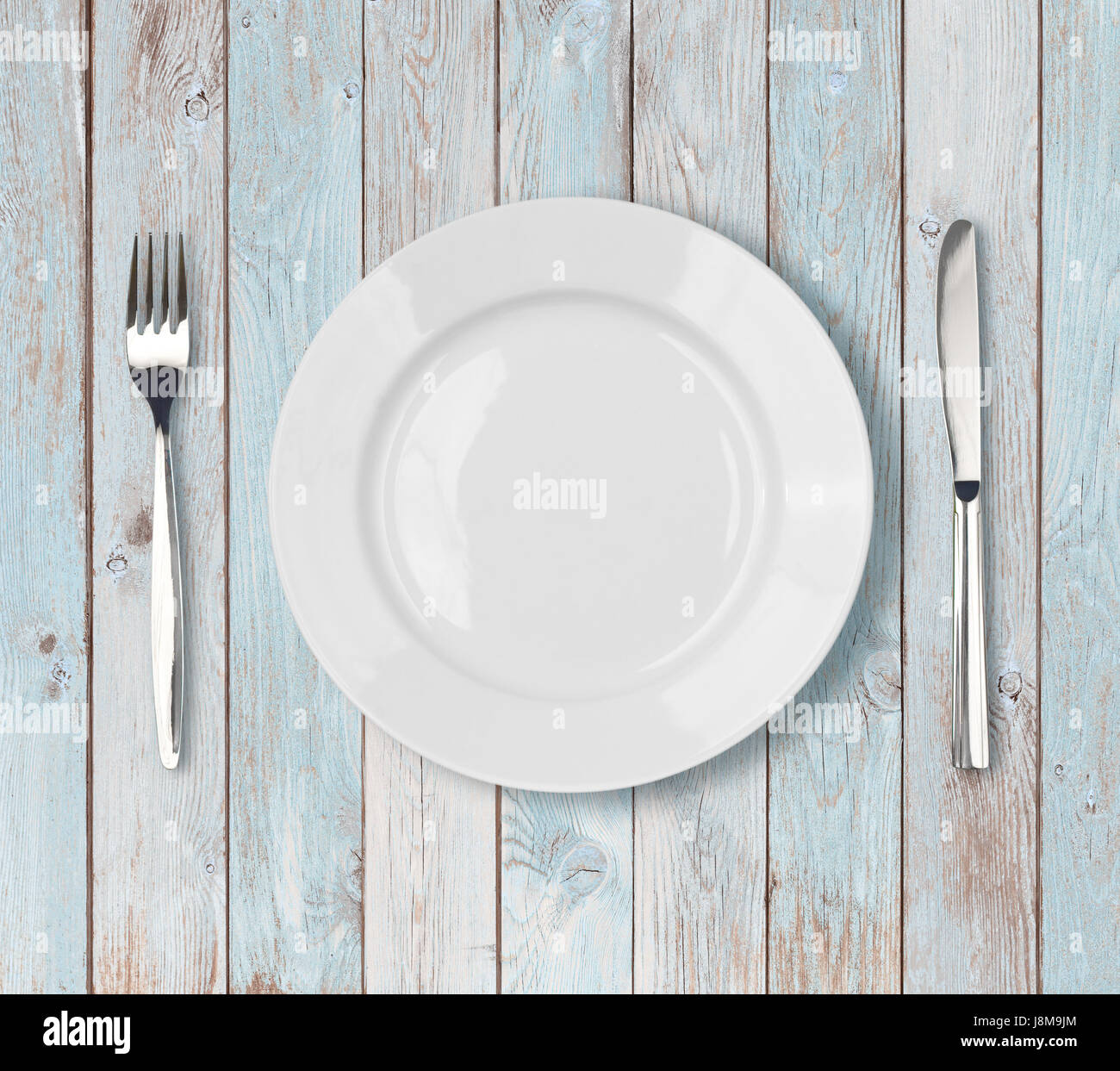 Bianco cena vuota impostazione della piastra blu sul tavolo di legno Foto Stock