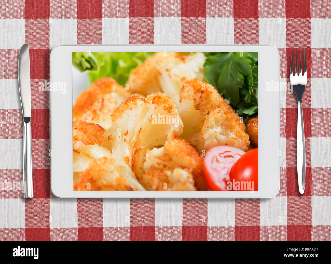 Tablet PC con lavastoviglie, forchetta e coltello sul rosso tovaglia controllati Foto Stock