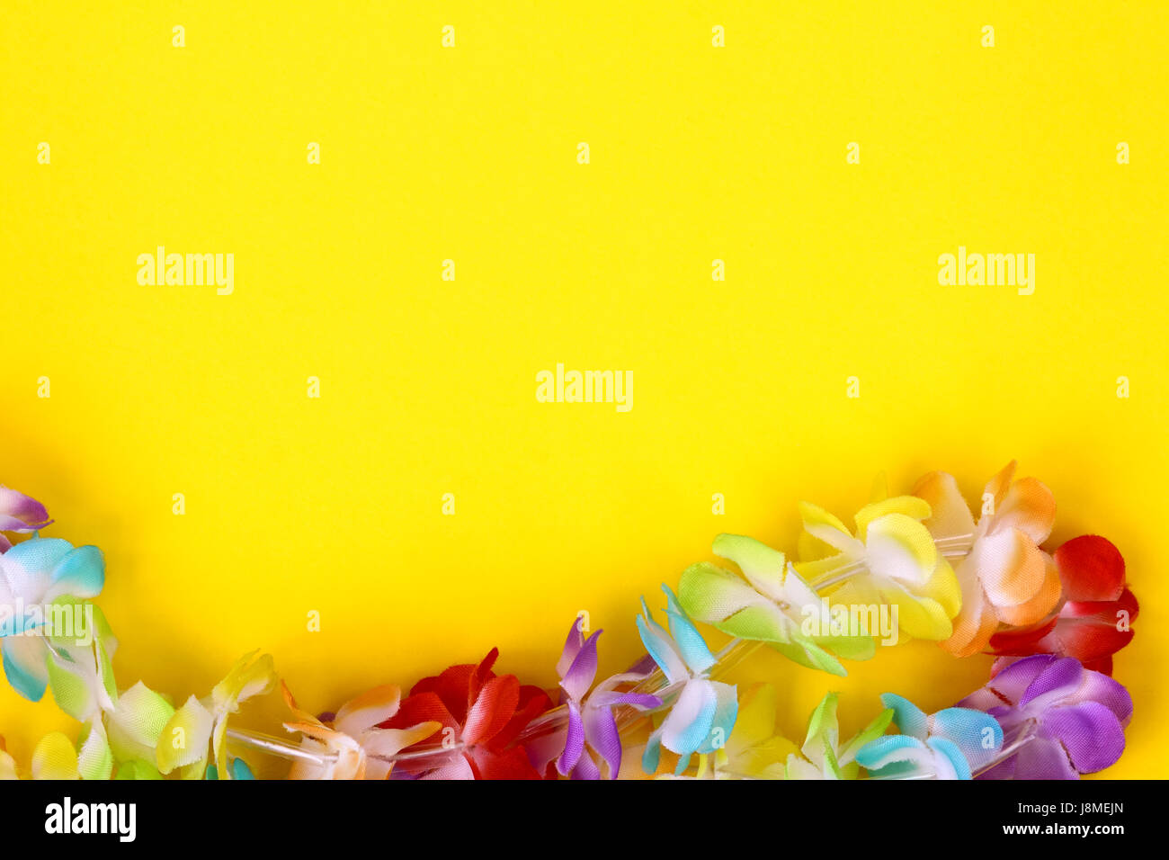Rainbow colorati fiori finti su una collana attorno a un semplice sfondo colorato con camera per spazio di copia Foto Stock