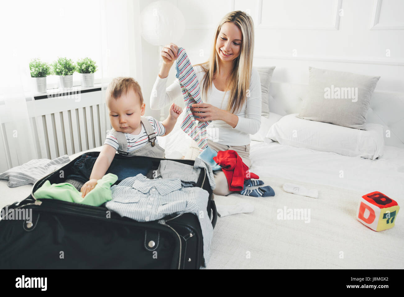 Viaggiare con i bambini. Felice madre con il suo bambino abiti di imballaggio per le proprie vacanze Foto Stock