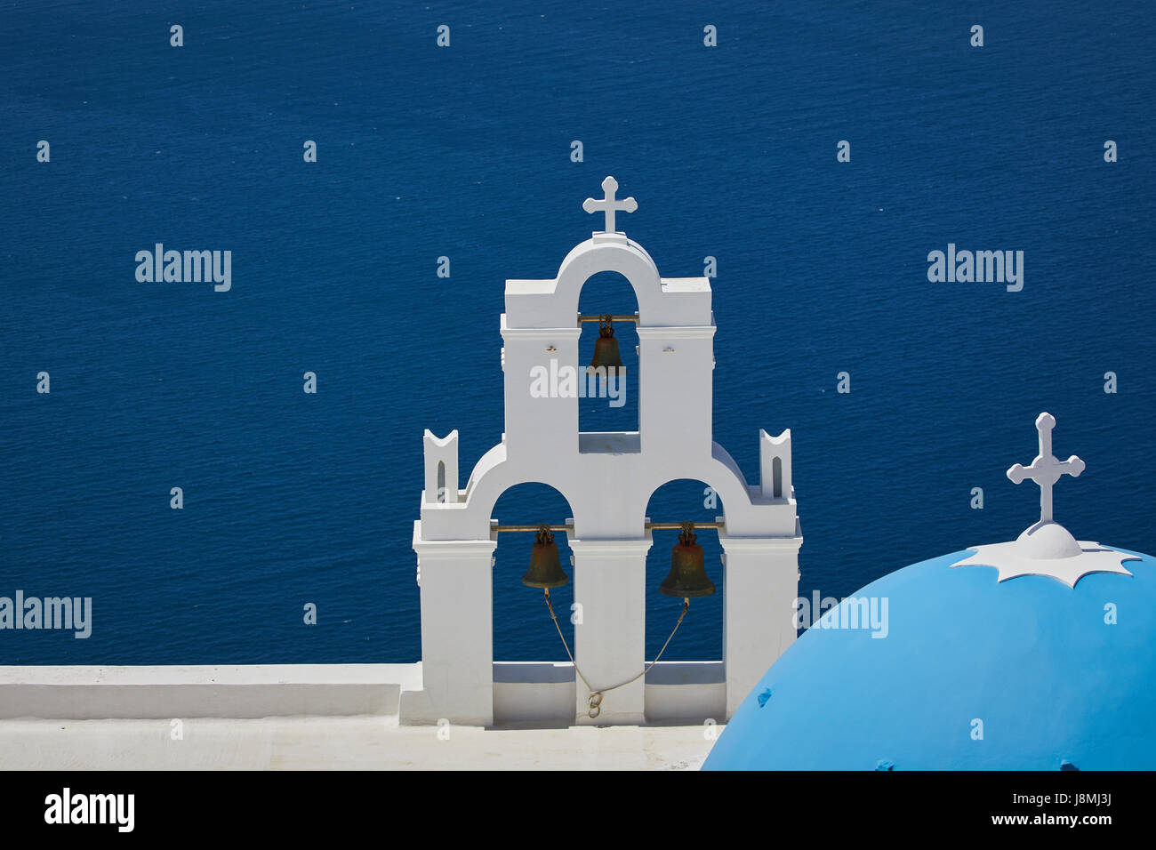 Vulcanica isola greca Santorini una delle isole Cicladi nel Mare Egeo. Fira capitale isole simbolo principale tre campane di Fira e blu Foto Stock