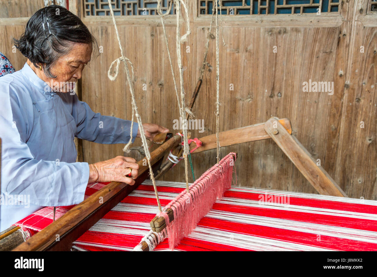 Yubei, Zhejiang, Cina. Senior tessitura donna al suo telaio. Foto Stock