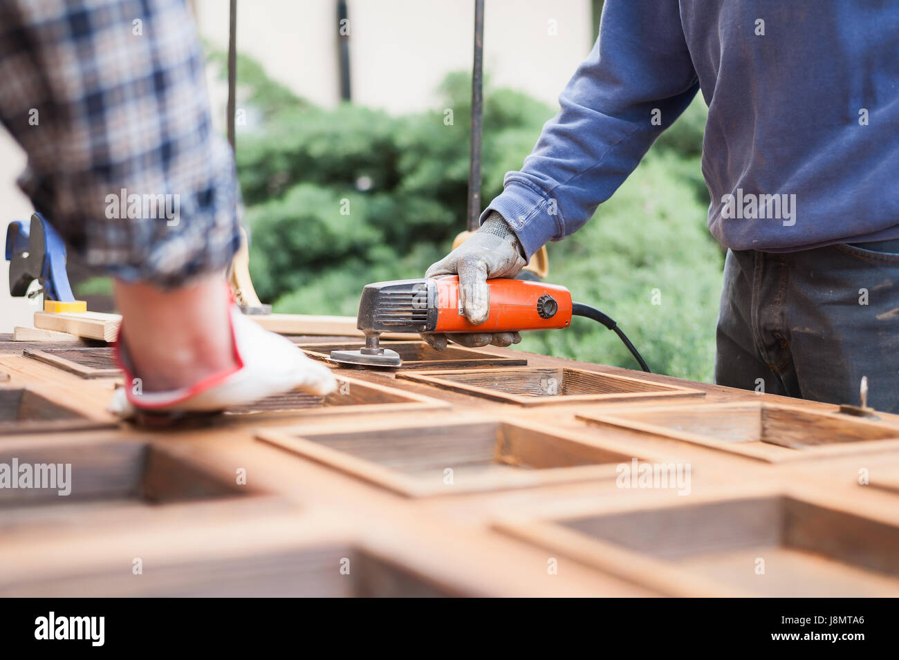 Carpenter al lavoro con la smerigliatrice angolare. La manutenzione e il restauro di una vecchia porta di legno. Foto Stock
