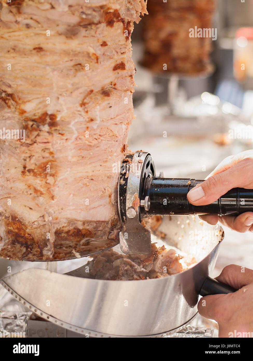 Le mani del cuoco che con coltello elettrico tagliare il döner kebab. Il Kebab è un piatto tipico della Turchia. Foto Stock